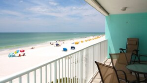Ein Balkon mit Blick auf einen Strand mit Sonnenschirmen und Menschen.