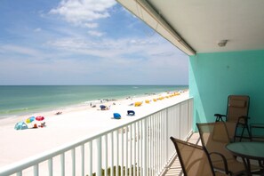 A balcony with a view of a beach with umbrellas and people. - Spacious beachfront comfortable 3-bedroom 2-bath.  Heated pool.  Great location for a FL vacation. (Madeira Beach)