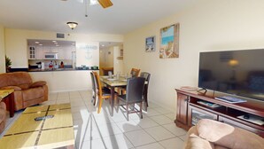Ein Wohnzimmer mit Fernseher, einer Couch und einem Essbereich.