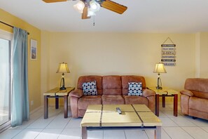 A living room with a brown sofa, two side tables with lamps, a wooden coffee table, and a ceiling fan.