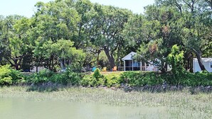 Une propriété située au bord d’un lac, avec une maison entourée d’une forêt dense et une zone herbeuse.