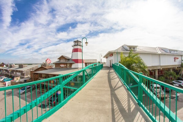 A coastal walkway with a lighthouse, a restaurant, and a parking area. - Studio Efficiency Ground Floor - Surf Song #116 (Madeira Beach)