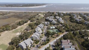 Luftaufnahme einer Küstenwohngegend mit Häusern, einem Golfplatz und einem Strand.