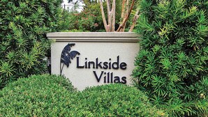 Schild für Linkside Villas mit Vogelkontur und üppigem Grünwerk drumherum.