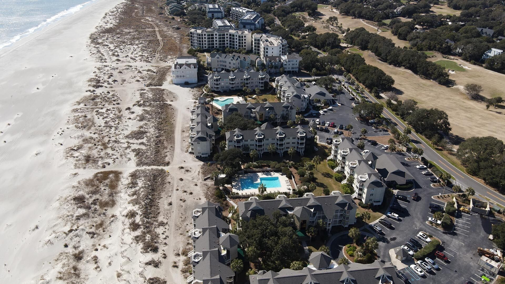 An aerial view of a coastal hotel with multiple buildings, a swimming pool, and a beach.