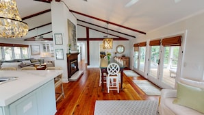 A spacious living area with a fireplace, wooden flooring, and a dining table with chairs.