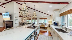 A spacious kitchen with a large island, modern appliances, and a dining area with wicker furniture.