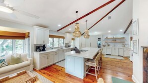 A spacious kitchen with white cabinetry, a central island, and wooden flooring.