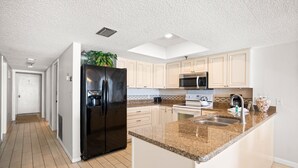 Une cuisine moderne dotée d’un îlot central, d’appareils électroménagers en acier inoxydable et de meubles de couleur claire.
