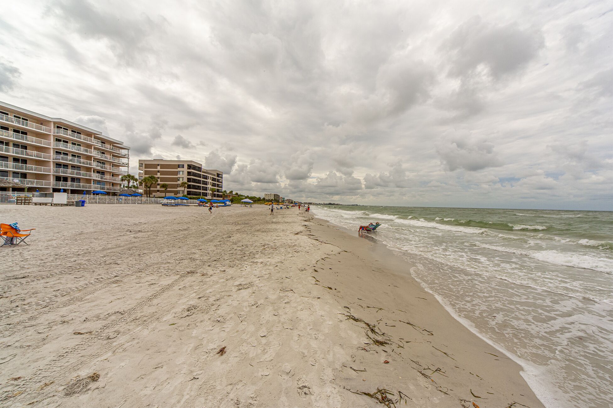 Een strand met een hotel op de achtergrond.