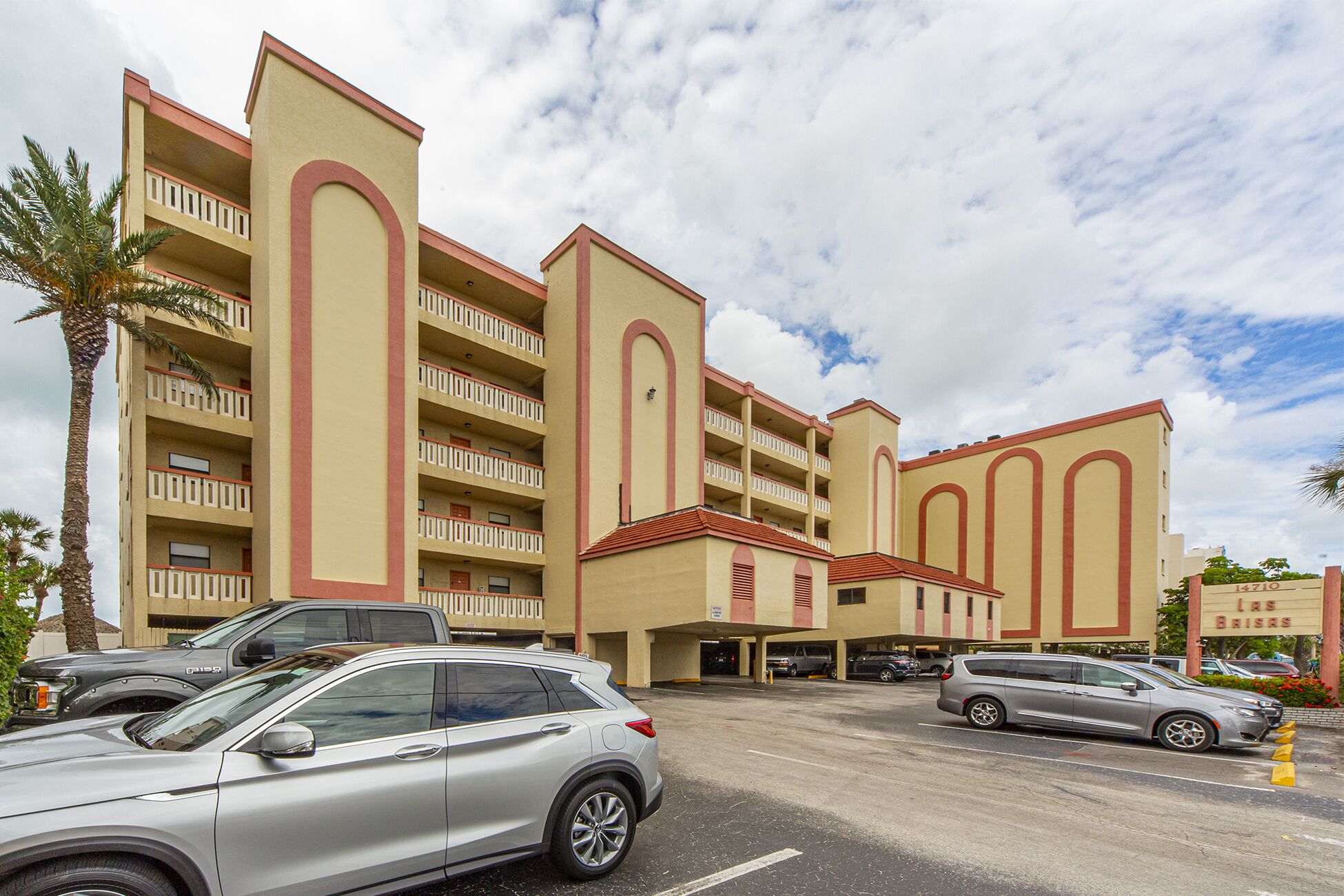 A multi-story hotel with a central atrium, parking garage, and a palm tree.