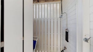 A bathroom with a white tiled wall, a shower area, and a door with a handle. - Walk to beach, screened porch, single level, updated kitchen and baths! (Isle of Palms)