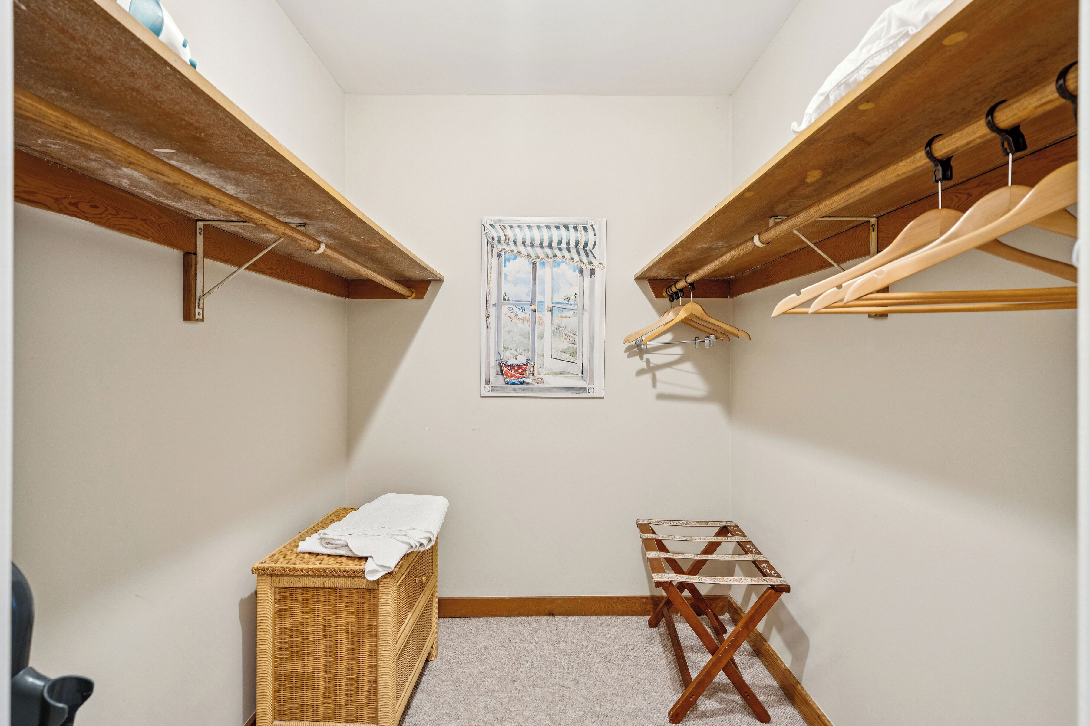 A small, well-lit room with a window, wooden shelves, a drying rack, and a wicker chest.