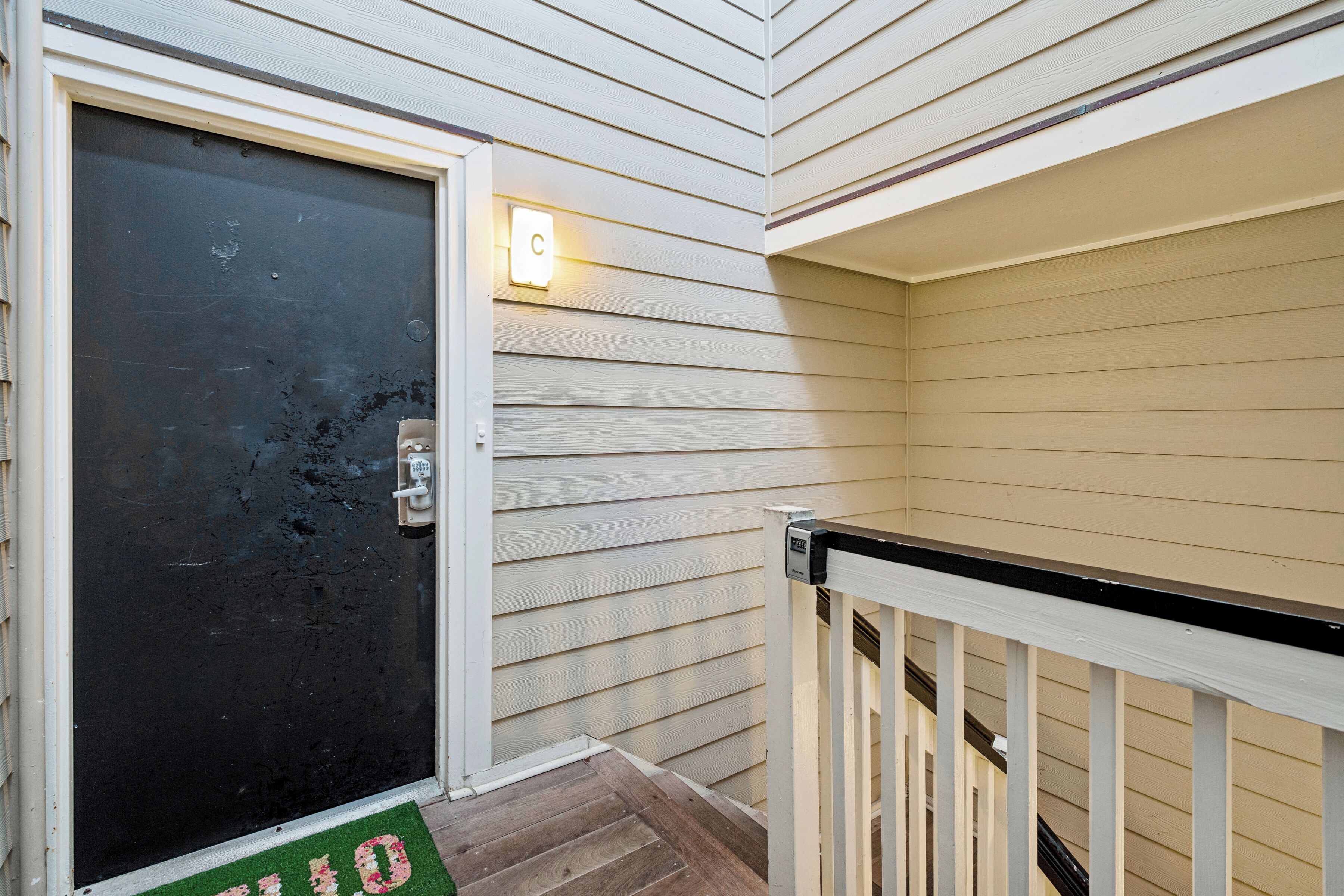 A front door with a mailbox, a light fixture, and a wooden deck.