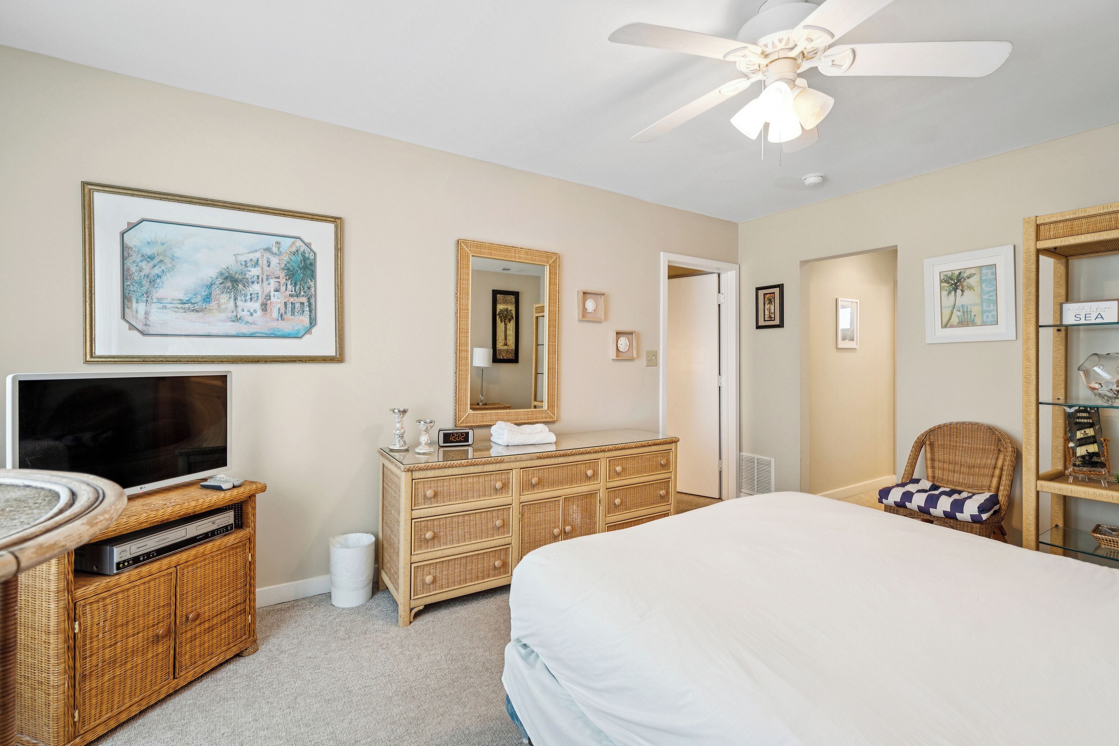 A bedroom with a bed, a dresser, a television, and a ceiling fan.