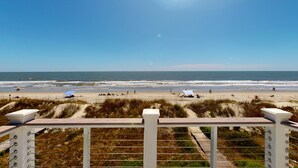 Uitzicht op het strand vanaf een houten terras met een leuning.