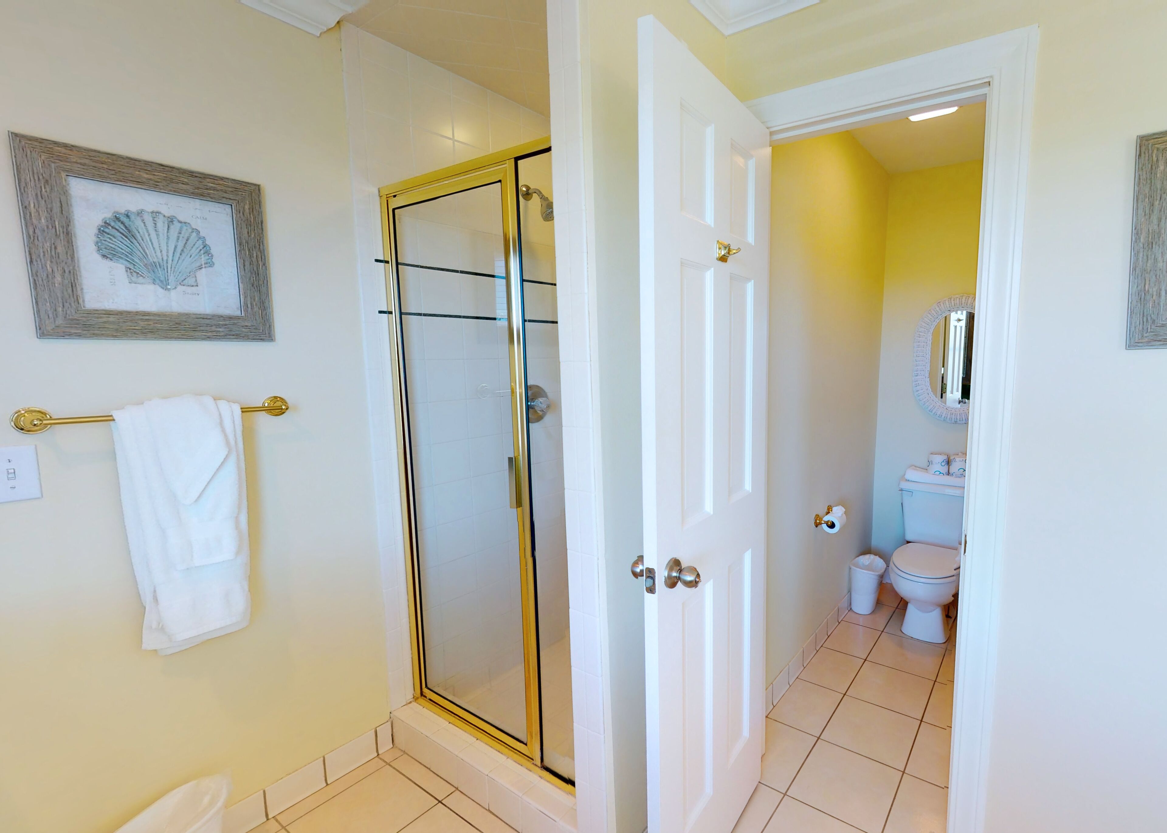 Une salle de bain avec une douche à parois de verre, des toilettes blanches et un tableau encadré au mur.