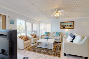 A living room with a white sofa set, a coffee table, and a ceiling fan. - Partial ocean-view condo with WiFi, hot tub & pool - close to entertainment (South Padre Island)