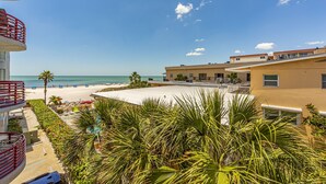 A beach view from a hotel balcony with a pool, palm trees, and a clear sky. - Large 1,225 sq ft Unit Beach Views Crimson #204 (Madeira Beach)