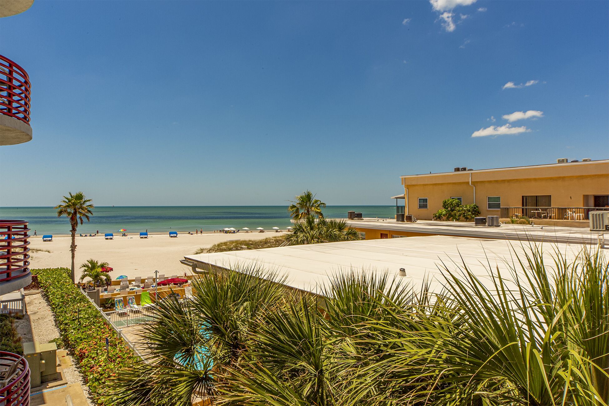 Blick auf einen Strand mit Pool, Palmen und einem Gebäude mit Klimaanlagen.