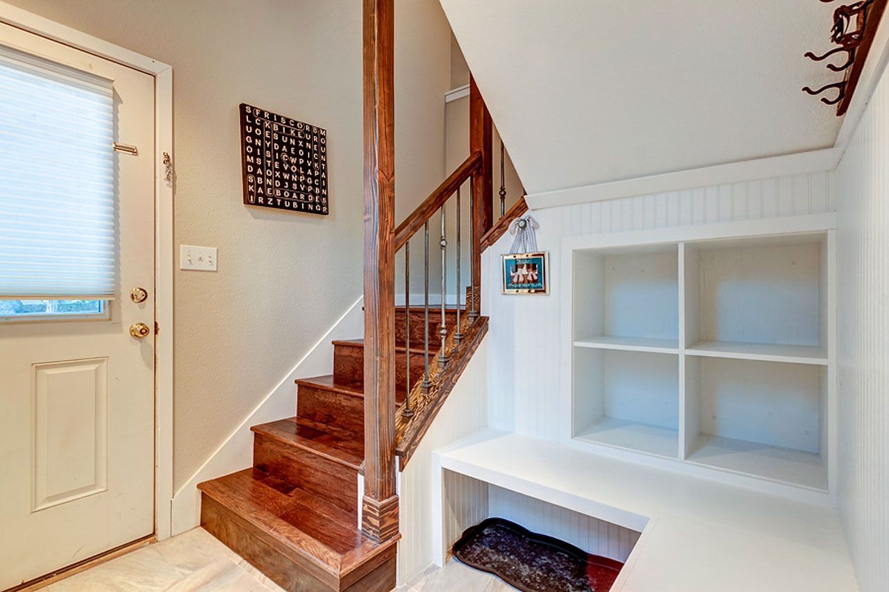 Un escalier avec des marches en bois et un mur blanc sur lequel est fixée une étagère.