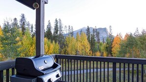 A barbecue grill on a wooden deck with a view of trees and a mountain in the background. - Crossroads Snowshoe Townhome: Great Views, On Rec Path (Frisco)