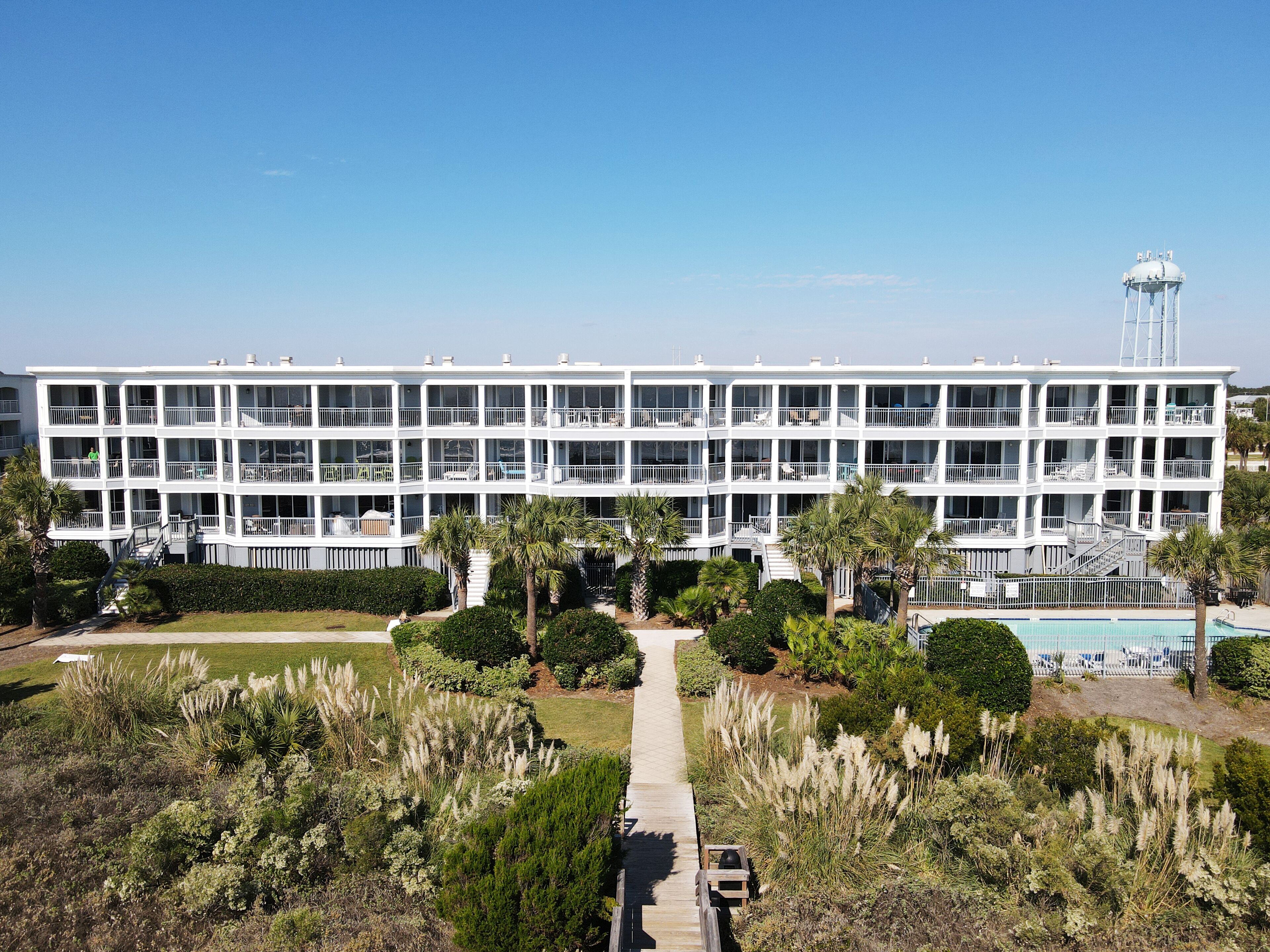 A multi-story hotel with balconies, a swimming pool, and a water tower in the background.