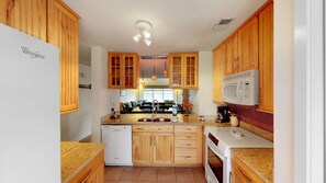 A kitchen with wooden cabinets, a built-in dishwasher, a microwave, and a stove. - Great home located near the beach with pool and tennis court access (Isle of Palms)