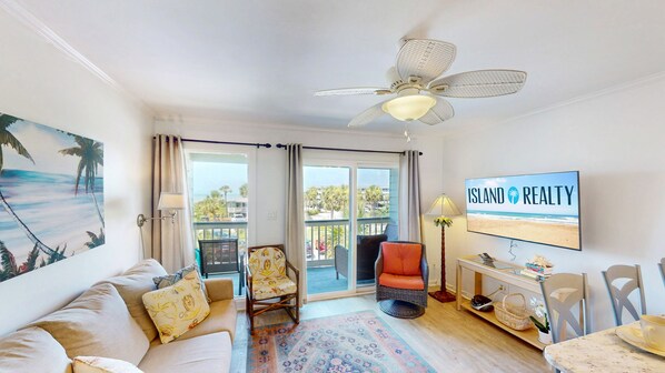 A living room with a sofa, chairs, a TV, and a balcony with a view of the beach. - Quaint Coastal Hideaway with Beach View! (Isle of Palms)