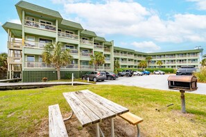 A multi-story hotel with balconies, a parking lot, and a picnic table. - Quaint Coastal Hideaway with Beach View! (Isle of Palms)