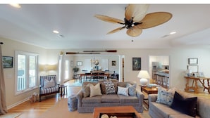 A spacious living room with a large ceiling fan, a dining area, and a kitchen in the background. - Beautiful home in Wild Dunes with a private pool and close beach access (Isle of Palms)