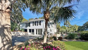 A two-story house with a covered porch and a fenced yard. - Beautiful home in Wild Dunes with a private pool and close beach access (Isle of Palms)