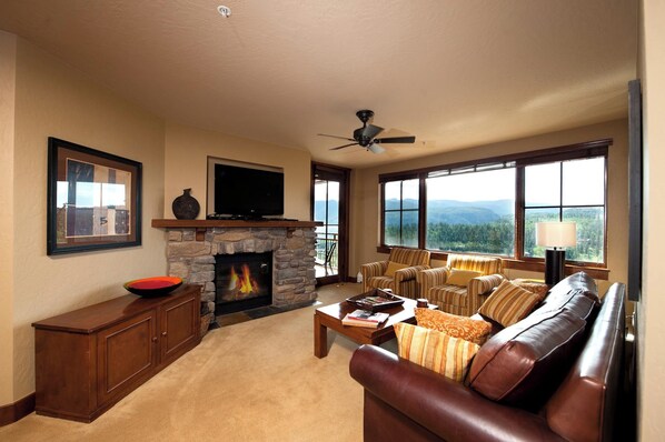 A living room with a stone fireplace, a television, and a sofa.