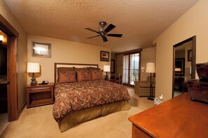 A hotel room with a large bed, a ceiling fan, a desk, and a chair.