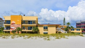 Hotel frente a la playa con varios balcones, una playa de arena y cielo despejado.