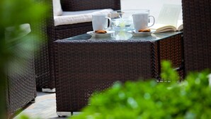 Wicker furniture with white cups and a book on a table.