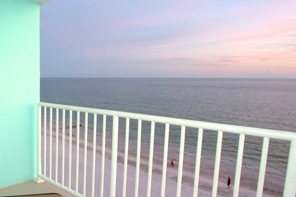A balcony with a view of the ocean and a beach.