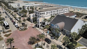 Een hotel aan de kust met zwembad, uitzicht op het strand en een parkeerplaats.