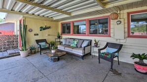 Un patio cubierto con un sofá, dos sillas y plantas en macetas.