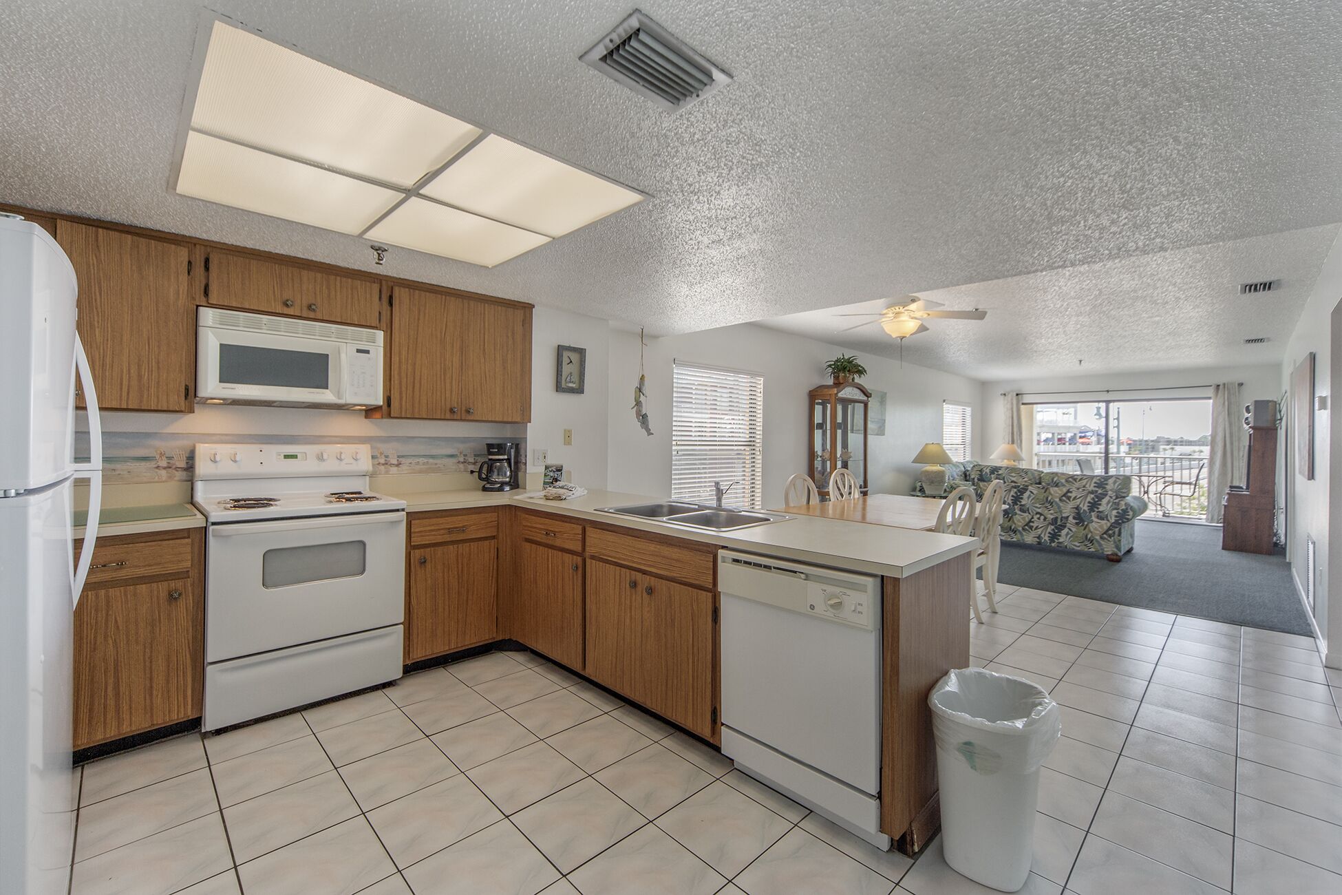 A compact kitchen with wooden cabinets, a microwave, stove, and a dishwasher.