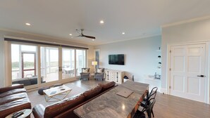 Ein geräumiges Wohnzimmer mit einer großen Schiebeglasdoor, die auf eine Außenpatio führt, einem Marmoresszimmer und einer gemütlichen Sitzecke mit Sofa und Sesseln.