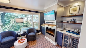A modern living room with a fireplace, a flat-screen TV, and a dining area with a round table. - Beautifully Updated Wild Dunes Luxury House (Isle of Palms)