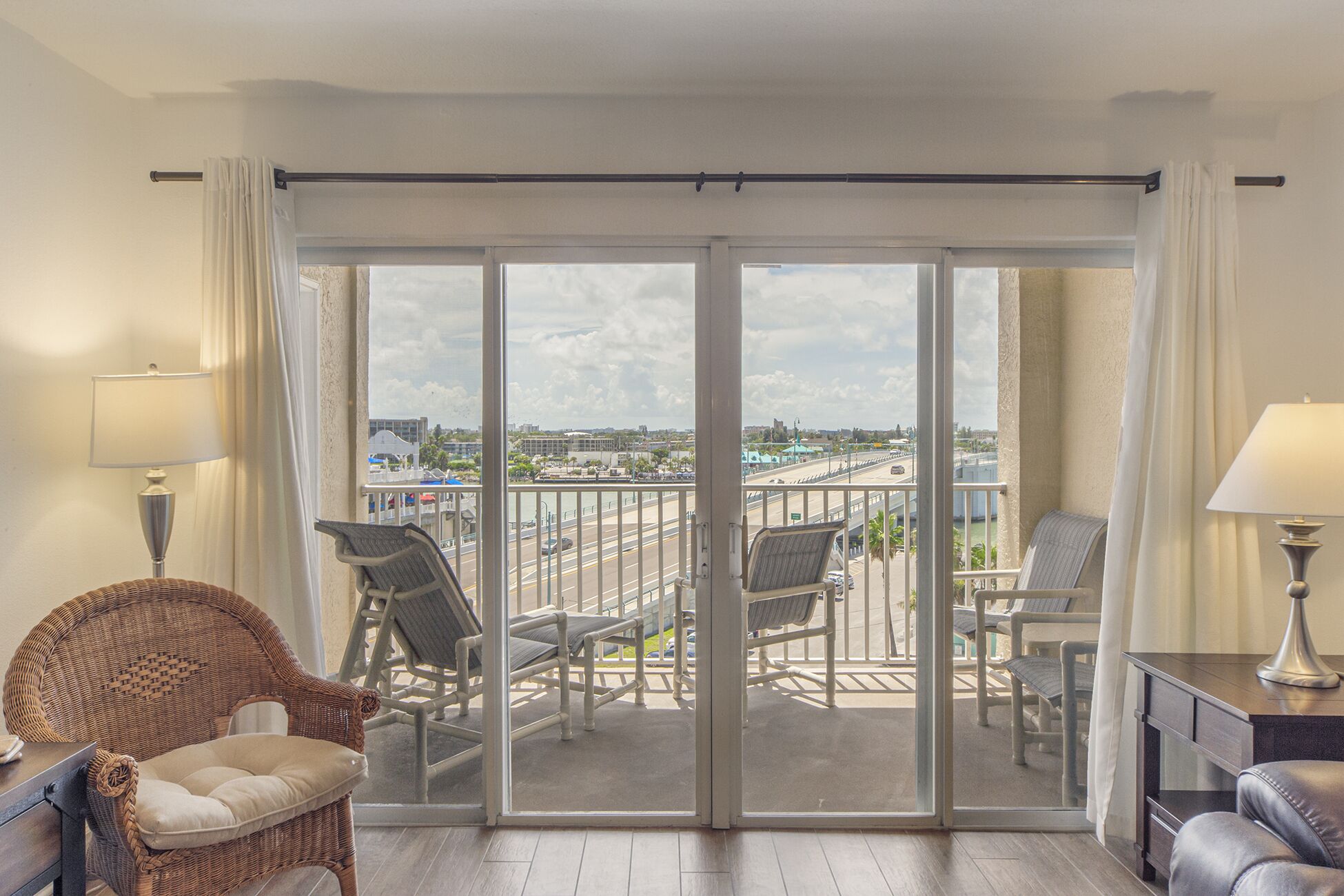 Een balkon met uitzicht op een stadsgezicht, rieten meubilair en een schuifdeur.