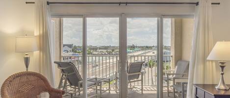 Een balkon met uitzicht op een stadsgezicht, rieten meubilair en een schuifdeur.