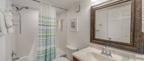 A bathroom with a shower, toilet, and sink.