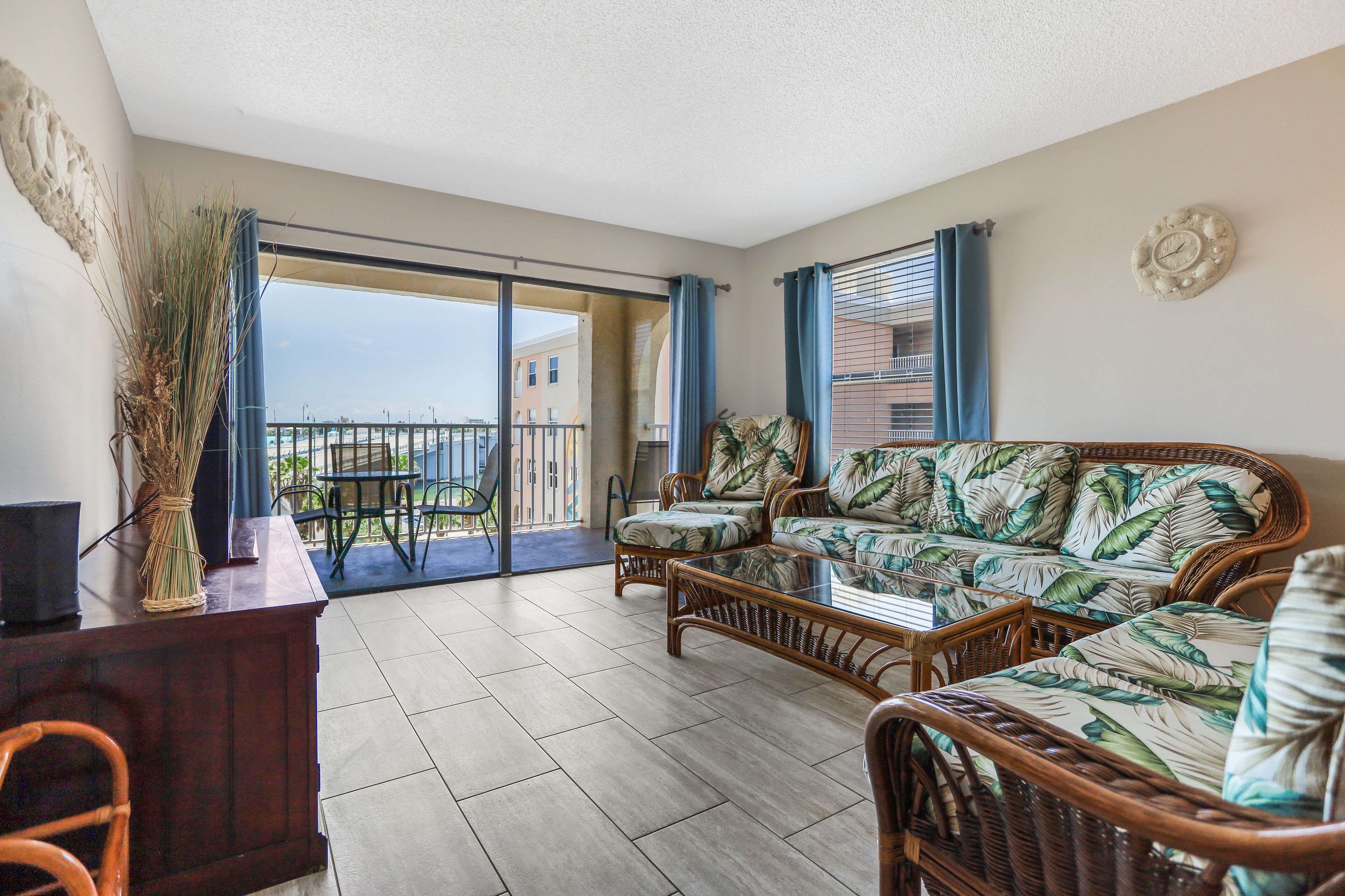 A spacious living area with a balcony, wicker furniture, and a view of the city.