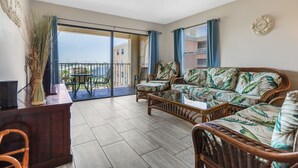 Un'ampia zona giorno con balcone, arredi in vimini e vista sulla città.
