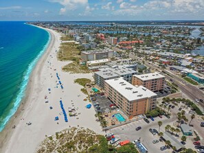 An aerial view of a coastal city with a beach, hotels, and a marina.