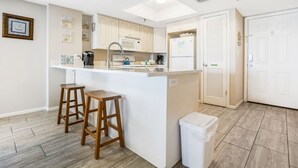 Una cucina moderna con isola centrale, sgabelli di legno e un cestino.