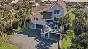 A two-story house with a large garage, a covered patio, and a view of the beach. - Fabulous oceanfront home with private beach access (Isle of Palms)